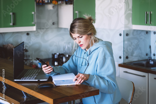 business woman looking at mobile phone while at home in the kitchen