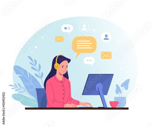 A woman works online. Vector illustration in a trendy flat style of a young pretty woman in headphones chatting online with customers on a computer at the desk. Isolated on background  © nadzeya26