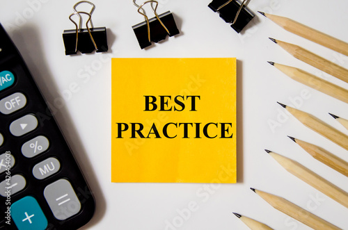 best practice word written on a yellow piece of paper and white background with pencils lying next to it photo