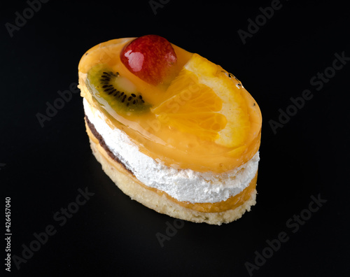 Pastry stuffed with berries and citrus fruits on a black background isolated, side view, confectionery product