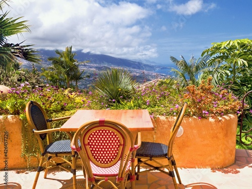 Garden landscape in the north of the island of Tenerife at about 300 meters above sea level in Santa Ursula. View over green plants and palm trees to the Orotava Valley. In the foreground is a small p