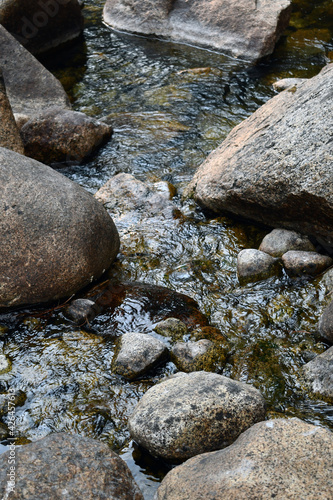 Vertical shot of river flowing through the stones