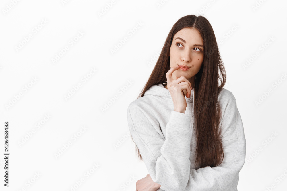 Pensive woman thinking what food order, looking up thoughtful, making choice or imaging something, pondering, standing over white background Pensive woman thinking what food order, looking up thoughtful, making choice or imaging something, pondering, standing over white background