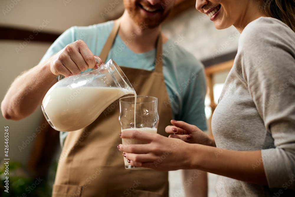 Close-up of man pouring milk into girlfriend's glass for breakfast in the morning. Close-up of man pouring milk into girlfriend's glass for breakfast in the morning.