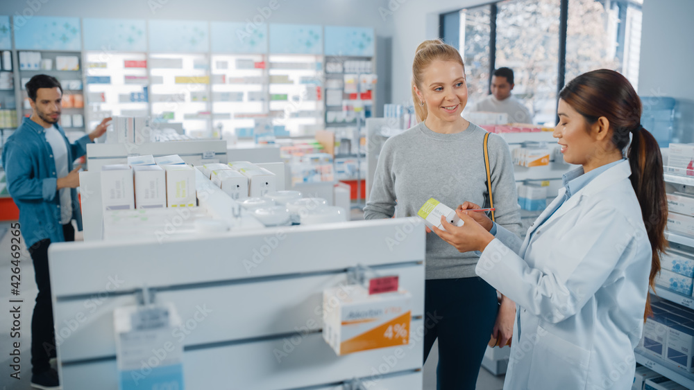 In Pharmacy Drugstore Diverse Group of Multi-Ethnic Customers Browsing Medicine. Professional Pharmacist Talks with Female Customer, Recommends Health Care Products, Supplements, Drugs
