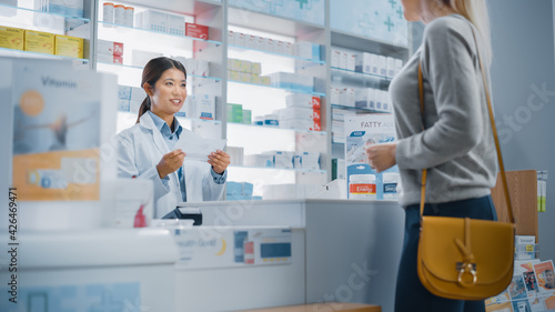 Pharmacy Drugstore Checkout Counter  Customer gives Prescription to Professional Female Pharmacist who Finds Medicine Package  Explains how to Use it.