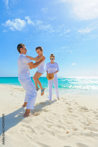 Family at the beach, mother, father and daughter playing on the sand dressed in white tropical outfits © TRAVEL EASY