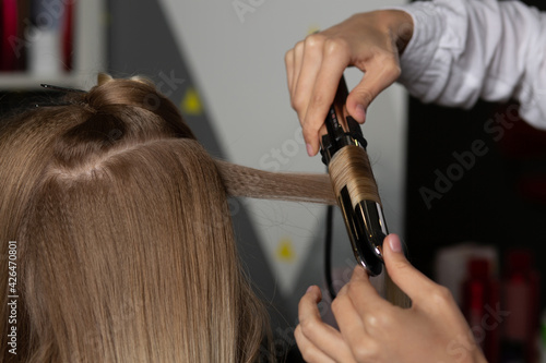 Hair stylist making curls to a blond woman