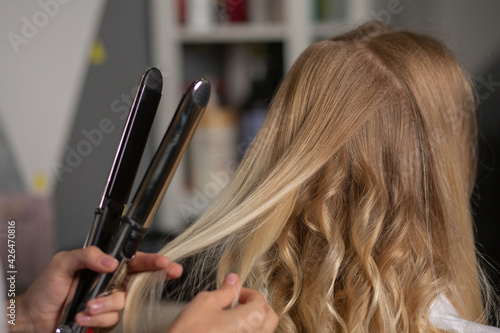 Hair stylist making curls with styling iron to a woman