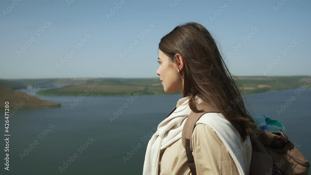 Side view of pleasant young woman with brown hair hiking with backpack at Bakota area. Happy female enjoying amazing nature near Dniester river. Side view of pleasant young woman with brown hair hiking with backpack at Bakota area. Happy female enjoying amazing nature near Dniester river.