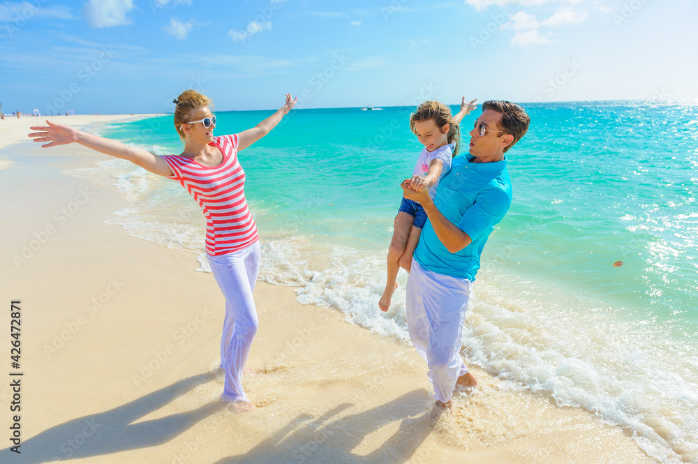 Family at the beach, mother, father and daughter playing on the sand dressed in colorful tropical outfits Family at the beach, mother, father and daughter playing on the sand dressed in colorful tropical outfits