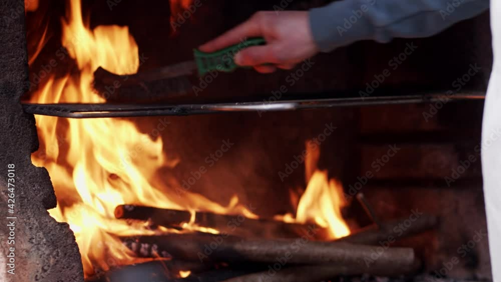 The cook cleans the grill with the brush The cook cleans the grill with the brush