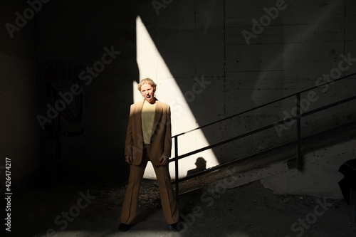 Creative portrait of young woman staying in the ray of light.