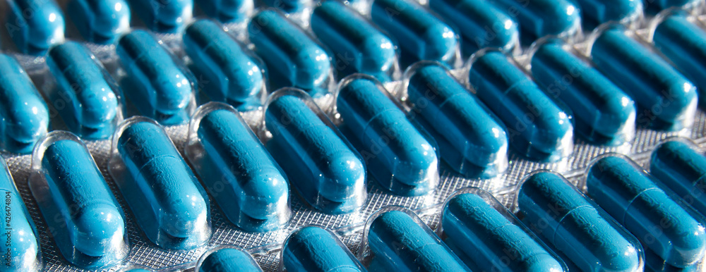 tablets in a soluble blue capsule. transparent packaging of the medicine. soft focus