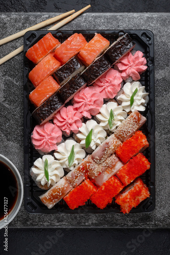 Sushi rolls on a dark stone background with bamboo sticks and soy sauce