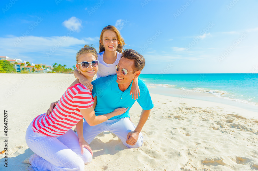Family at the beach, mother, father and daughter playing on the sand dressed in colorful tropical outfits Family at the beach, mother, father and daughter playing on the sand dressed in colorful tropical outfits