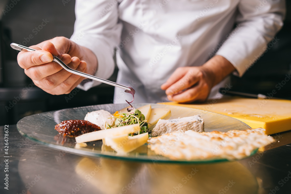 Chef decorates a cheese plate with tweezers