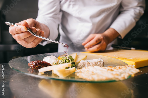 Chef decorates a cheese plate with tweezers
