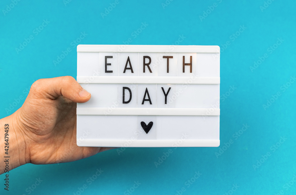 Earth Day lettering background, man holding lightbox with text message, environment protection concept Earth Day lettering background, man holding lightbox with text message, environment protection concept