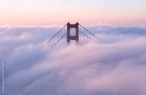Платно Golden Gate Bridge covered in clouds during the sunset in the evening in Califor