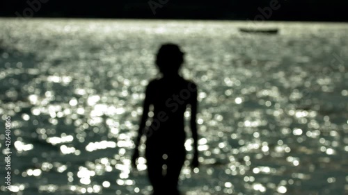 Defocused shoot of siluette of woman standing against lake on sunny weather. Slow motion shoot. Vacations relax concept for background. photo