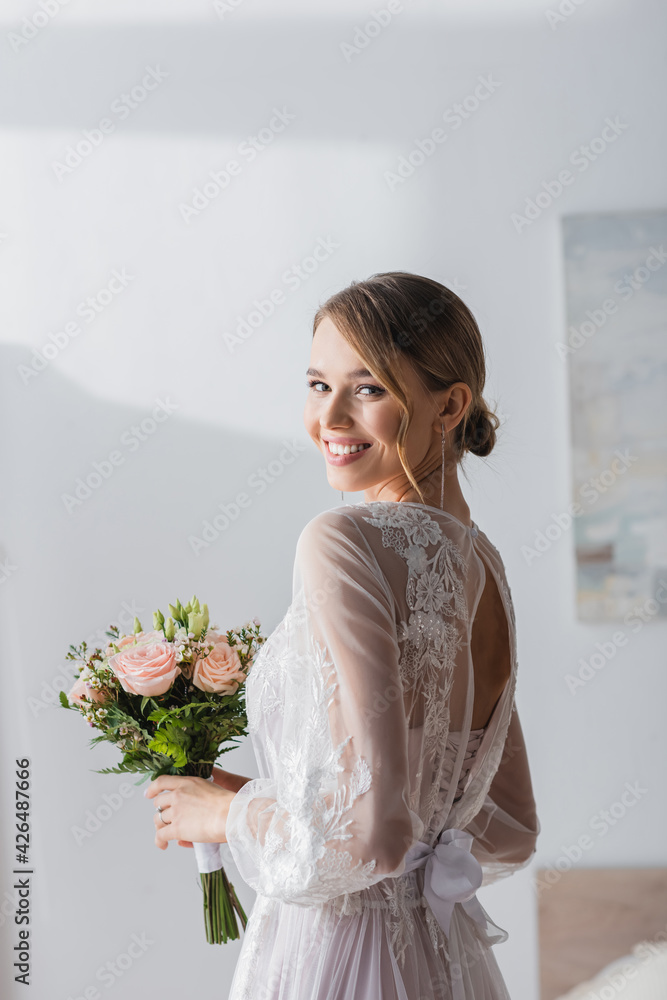 happy bride with wedding bouquet smiling at camera at home. happy bride with wedding bouquet smiling at camera at home.