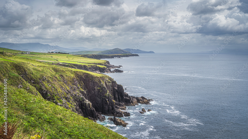 Cliffs, beautiful coastline and mountain range in Dingle Peninsula, scenic Wild Atlantic Way with dramatic storm sky, Kerry, Ireland