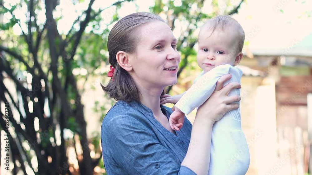 Happy family mom and little girl. Mother holds babygirl in her hands, outdoors Happy family mom and little girl. Mother holds babygirl in her hands, outdoors