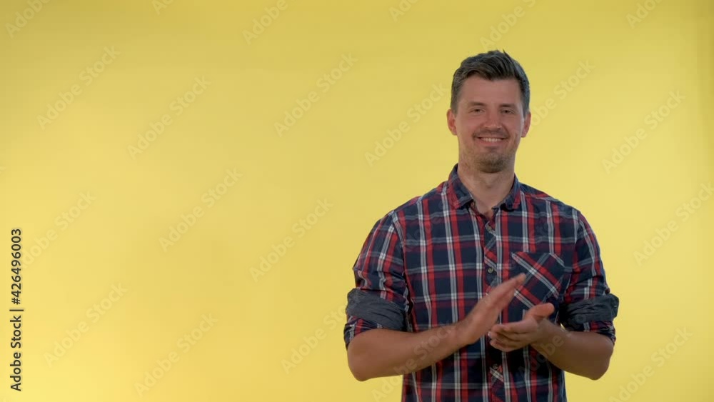 Portrait of smiling young man giving applause to somebody on yellow background. Portrait of smiling young man giving applause to somebody on yellow background.