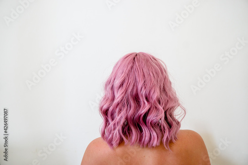 Back of woman's head with curly short pink hair