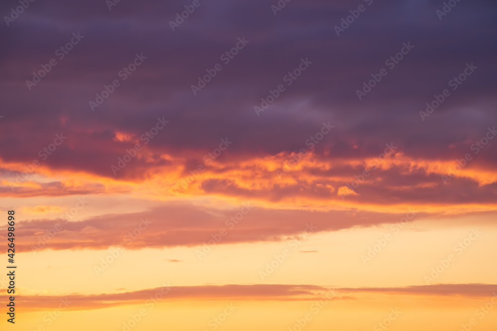 Bright violet or purple clouds at epic orange sunset sky background.