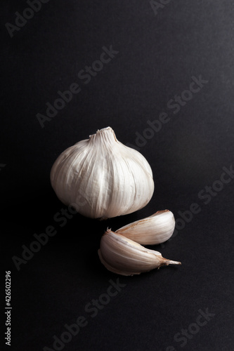 still life of garlic heads and garlic cloves on black background.  healthy ingredients food concept.