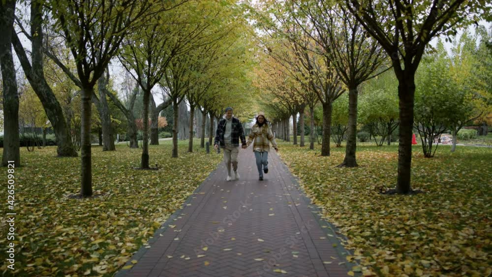 Zoom shot of happy young lovers running with holding hands along path. Zoom shot of happy young lovers running with holding hands along path.
