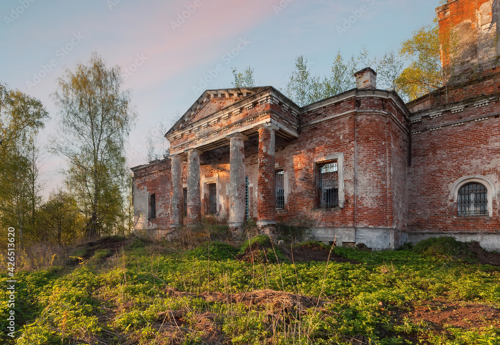 Portico with columns of an old, abandoned, brick church at sunset