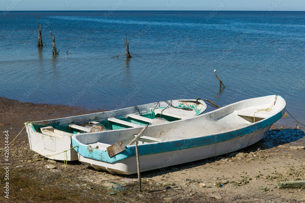 Two Mexican Panga fishing boats beached on the sand at low tide along the Bay of Campeche, Campeche, Mexico. Two Mexican Panga fishing boats beached on the sand at low tide along the Bay of Campeche, Campeche, Mexico.