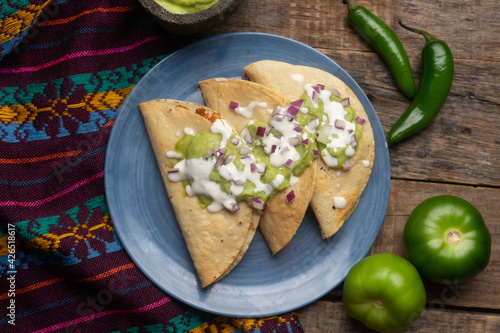 Fried tacos with guacamole and sour cream on wooden background. Mexican food