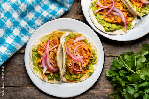 Chicken tinga tacos with guacamole and onion on wooden background. Mexican food