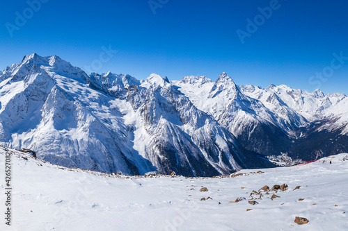 Caucasus Mountains, Panoramic view of the ski slope with the mountains Belalakaya, Sofrudzhu and Sulakhat on the horizon in winter day. Dombai ski resort, Western Caucasus © evgenii