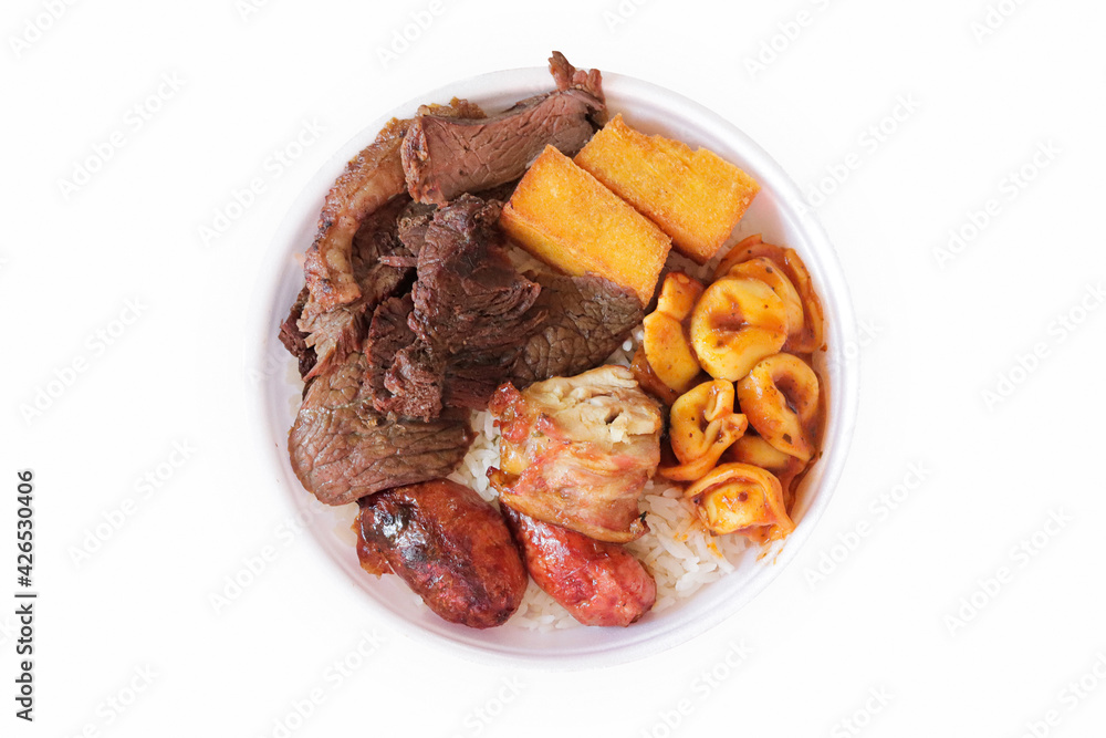 Marmitex with meat, sausage, chicken, fried polenta, capeletti, and rice in a white bowl - packed lunch - Brazilian Food - White Background - Top view.