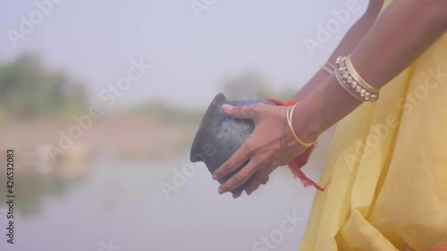 girl in yellow saree putting ashes in water slow motion asthi visarjan. photo