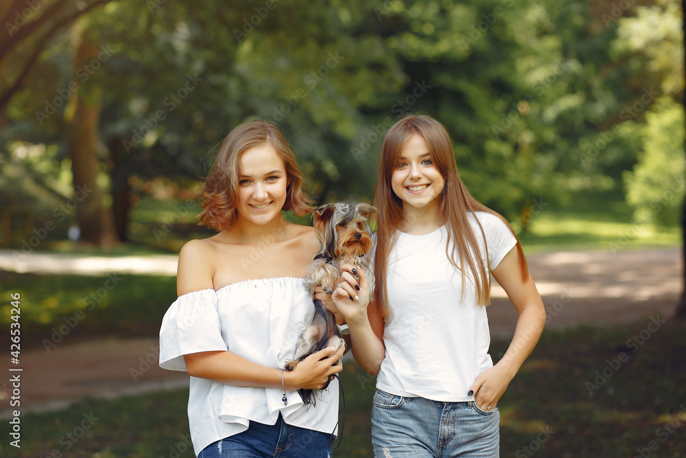 Fototapeta premium Two cute girls in a park playing with little dog