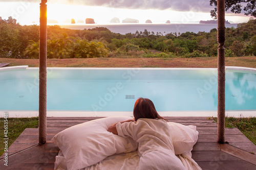 Happy woman traveler enjoy Beautiful ocean view, Tourist relaxing in tropical luxury resort with swimming pool. Leisure, travel and summer vacation concept