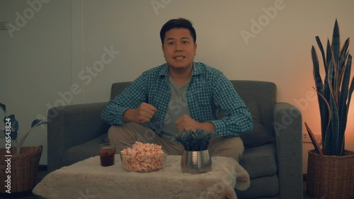 Asian men sit and win their favorite teams broadcasting live football matches.