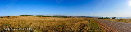 Panorama of the landscape with a dirt road going into the distance. In the background, the Kama River. Karakulinsky district. Udmurt Republic, Russia.