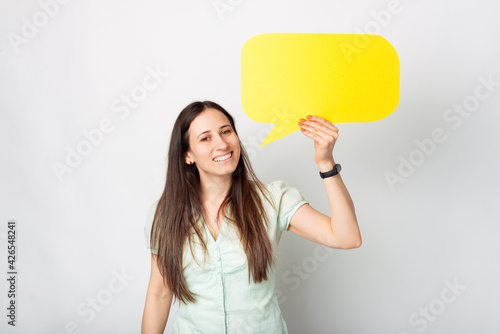 Photo of smiling beautiful young woman holding blank yellow speech bubble