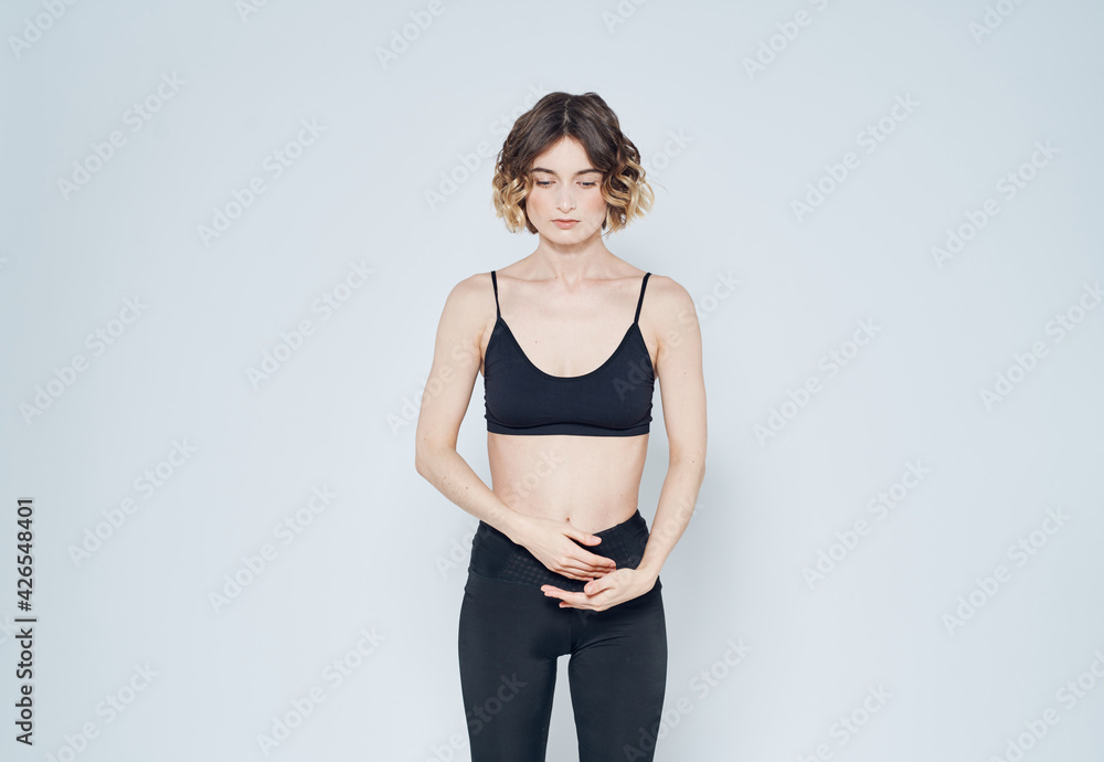 Woman gestures with her hands on a light background sport fitness leggings model Woman gestures with her hands on a light background sport fitness leggings model