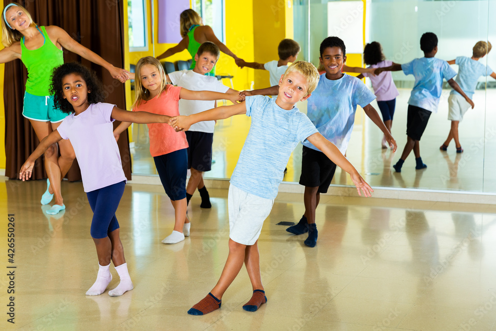 Tweenagers in pairs learning to dance active boogie-woogie with woman choreographer in modern class
