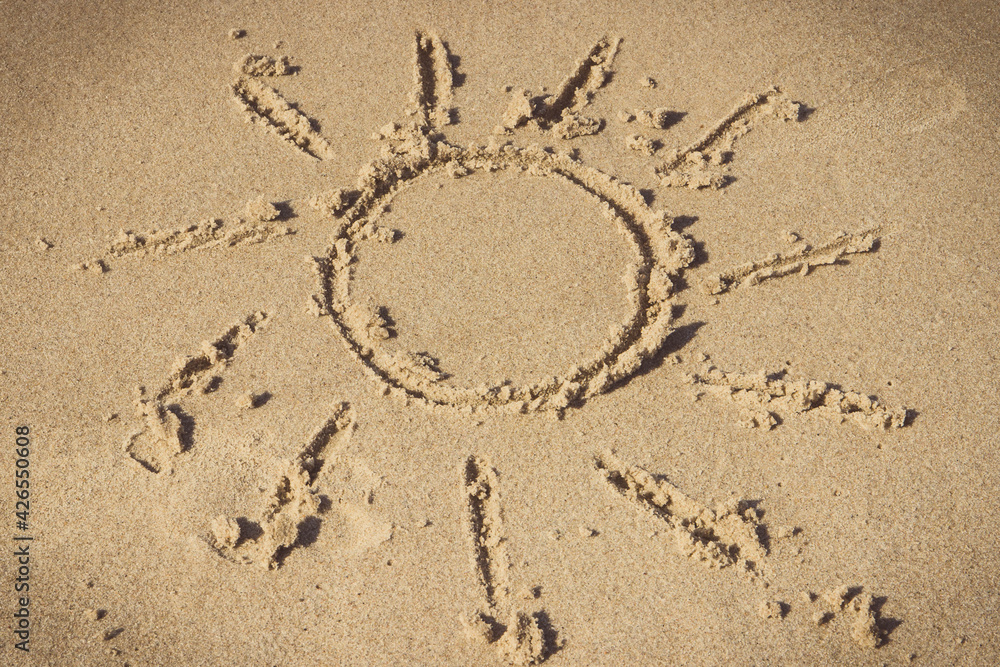 Shape of sun written on sand at beach. Vacation time