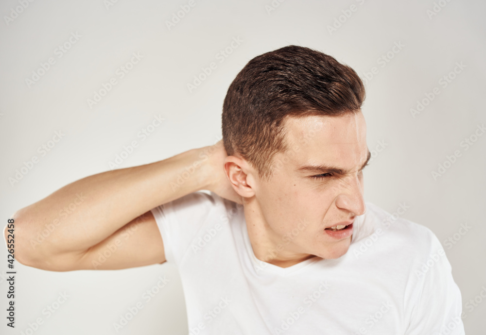 A man in a white T-shirt gestures with his hands on a gray background stress irritability A man in a white T-shirt gestures with his hands on a gray background stress irritability
