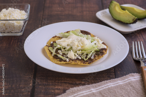 Traditional Mexican food. Tostada with beans, cream, lettuce and cheese, accompanied by avocado slices.